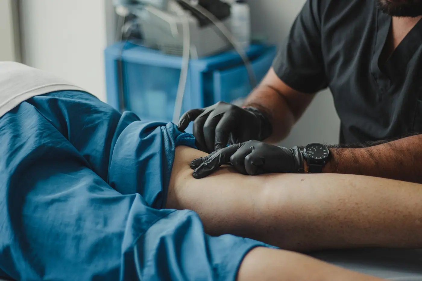 A healthcare professional in gloves provides treatment to a patient in a medical setting.