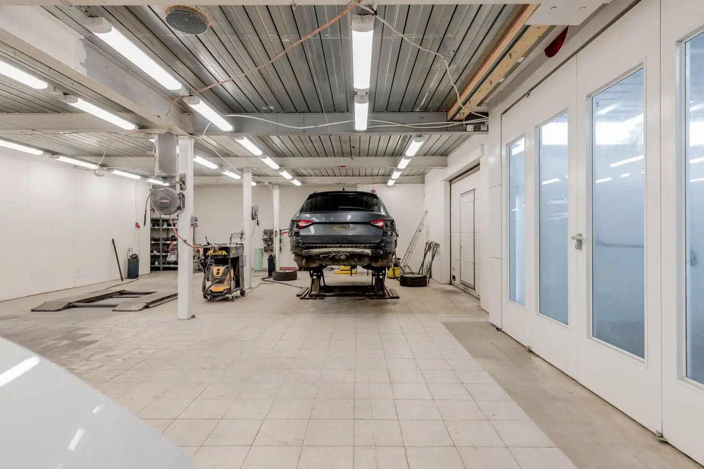 Well-lit garage with a car on a hydraulic lift ready for repair