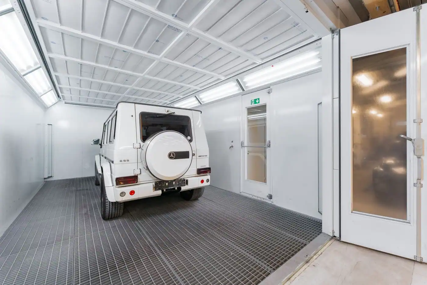 White luxury SUV parked inside a bright, modern automotive garage