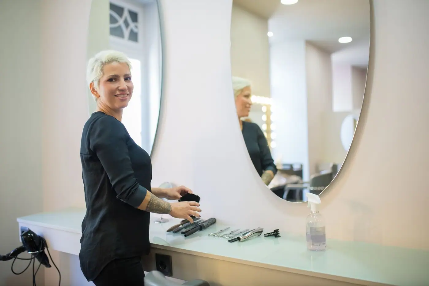 A hair stylist in a modern salon with tools and a mirror