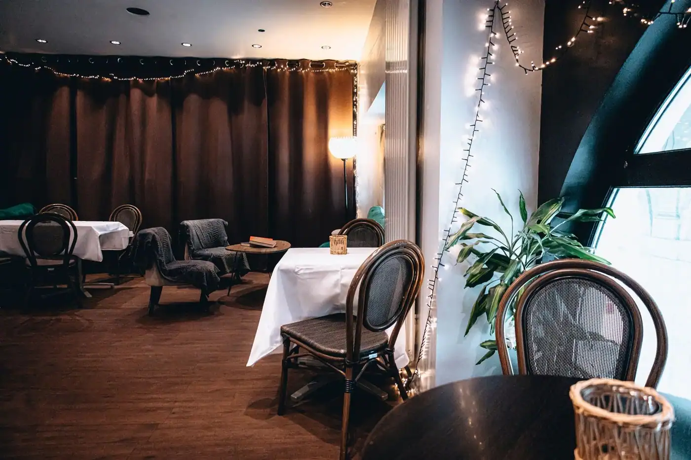 A warm, inviting indoor café setting with string lights and elegant table arrangements