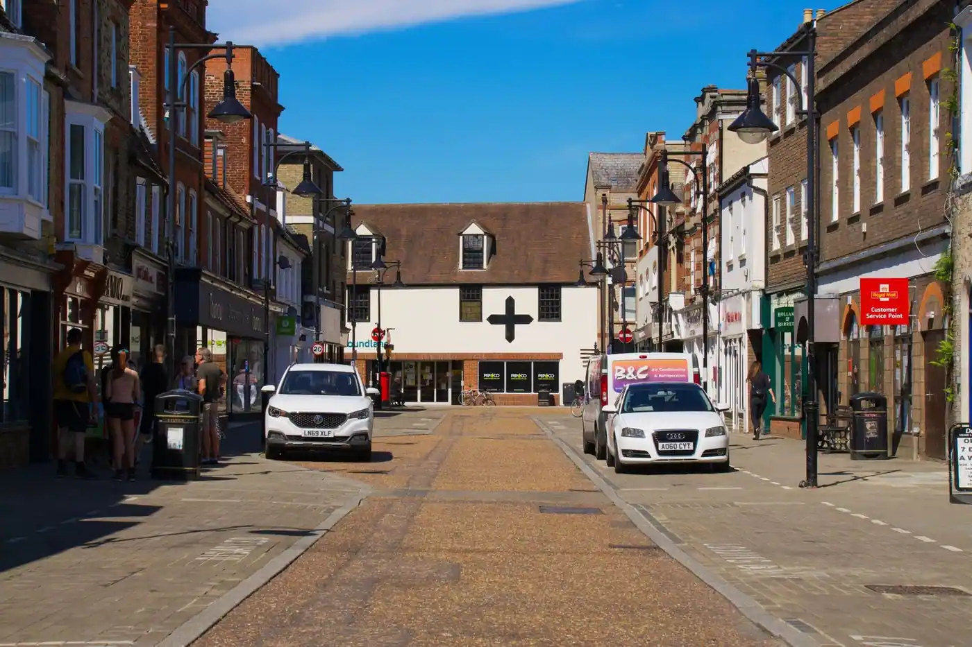 Sunny day on a lively street with shops and parked cars