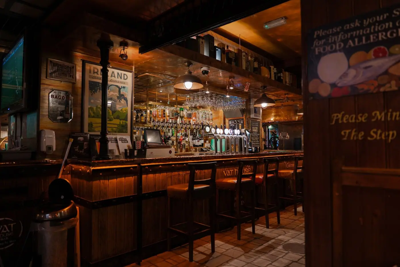 Warm, inviting interior of an Irish pub with a wooden bar counter and stools