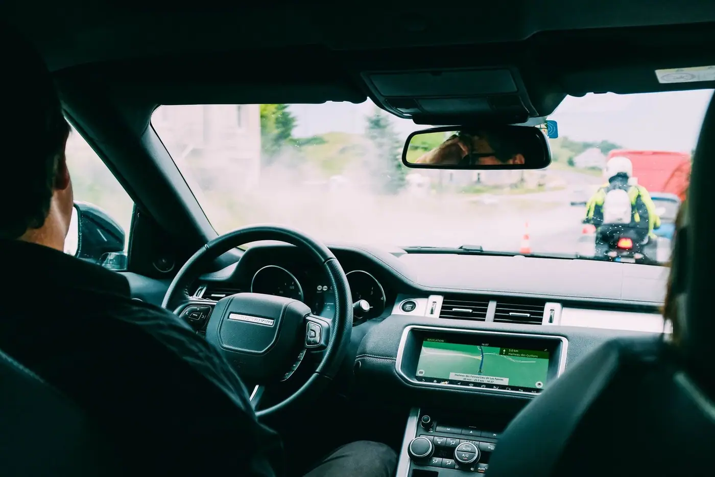 Inside a car, with a navigation screen and traffic on the road ahead