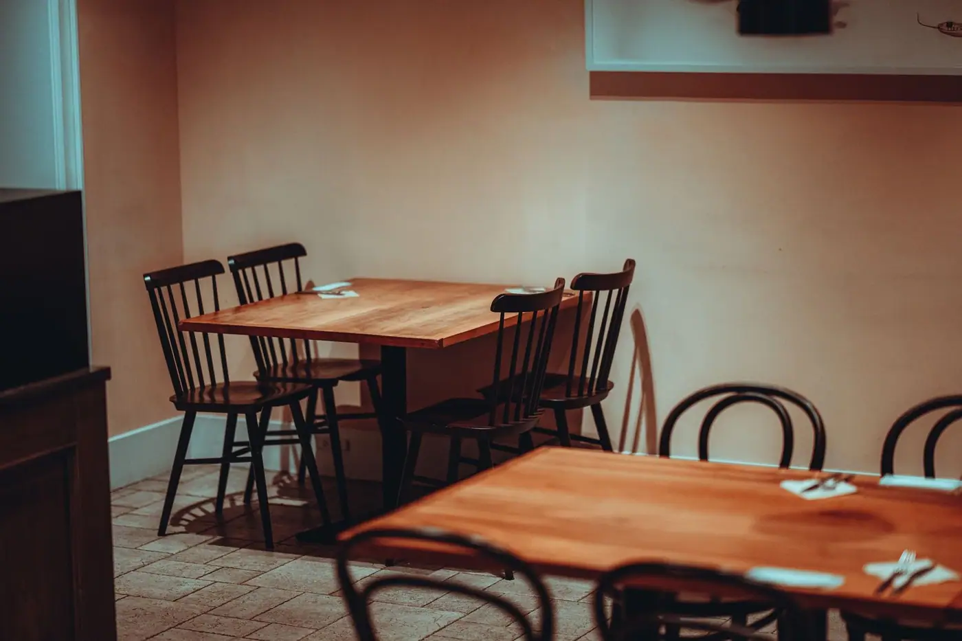 A minimalist restaurant interior with wooden tables and classic chairs