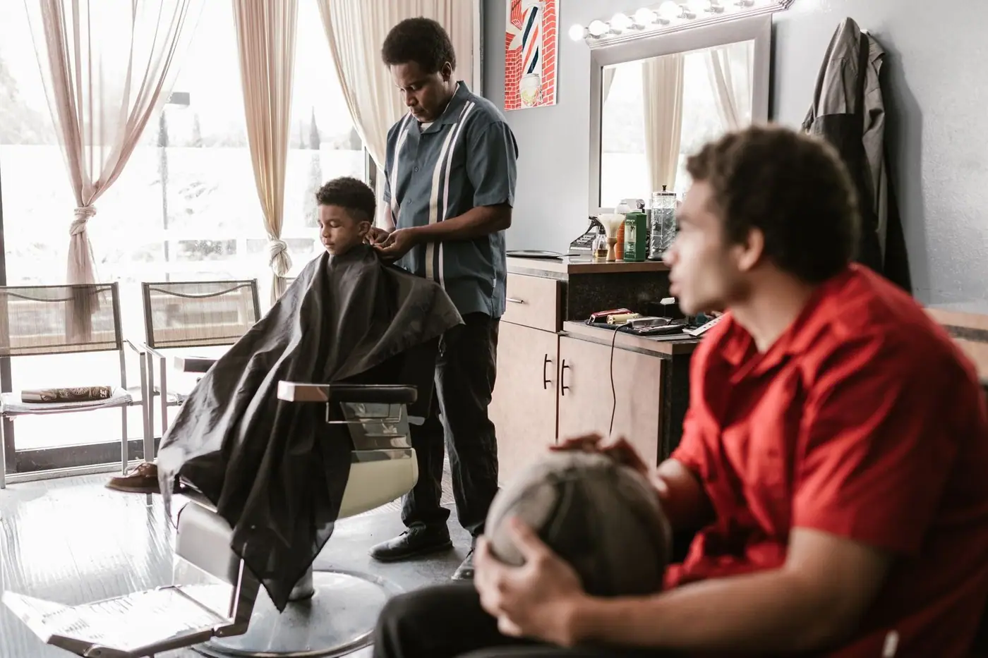 Barber styling a young boy's hair in a lively barbershop atmosphere
