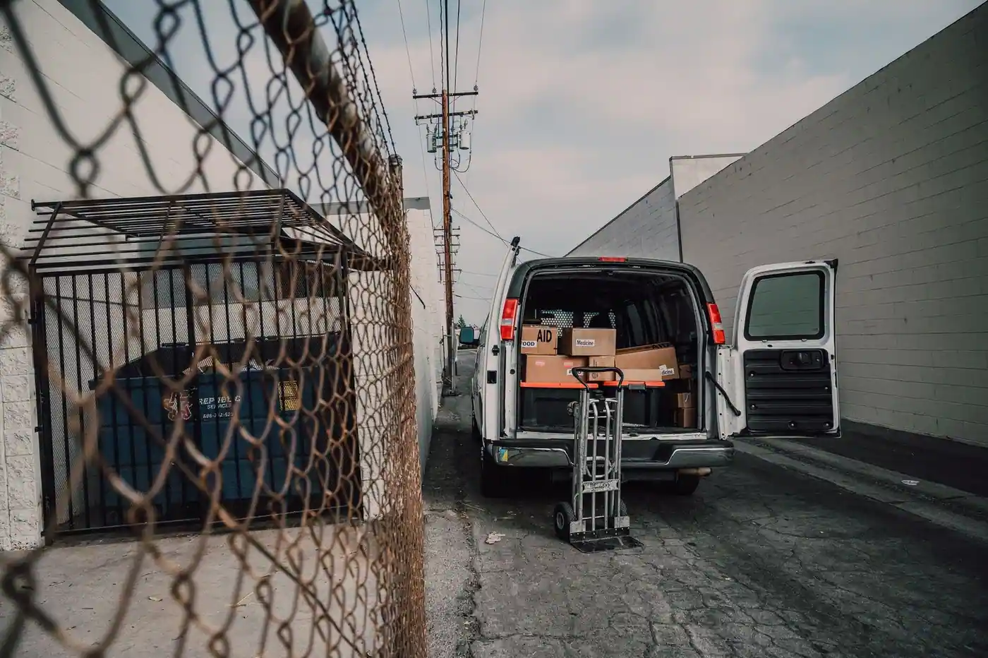 An open van loaded with boxes in an alley.