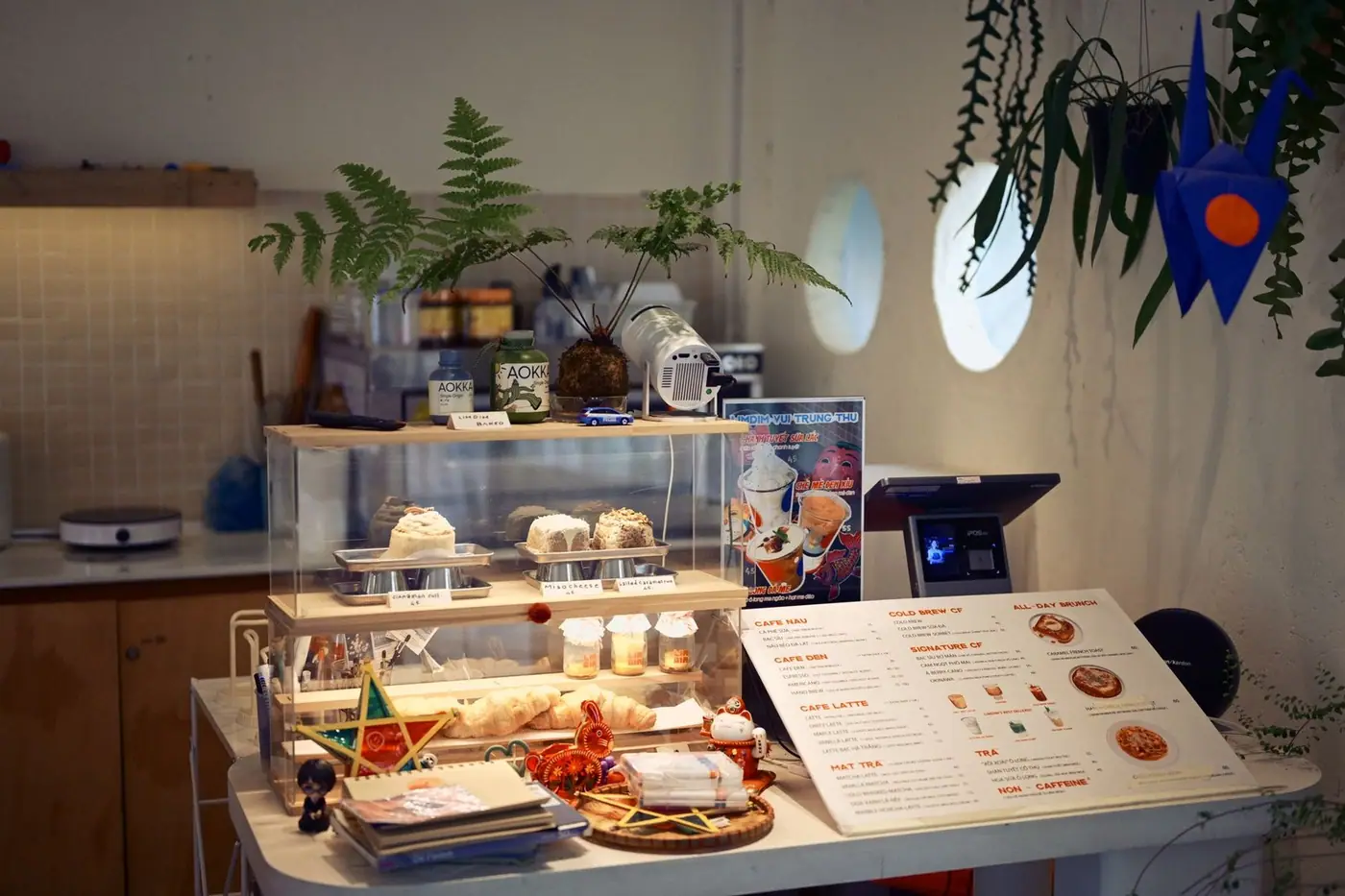 Coffee shop interior with a pastry display, ferns and a menu on the counter