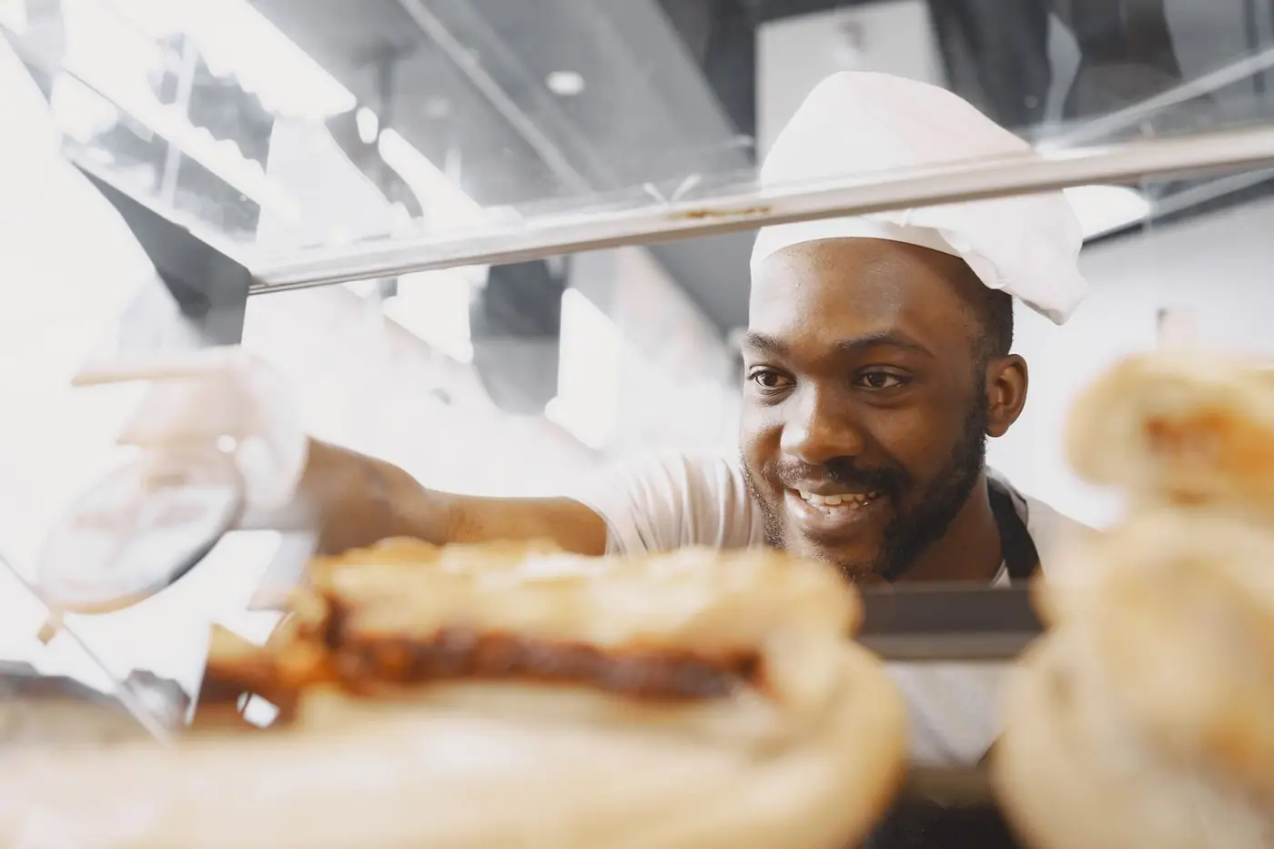 A cheerful baker arranging fresh bread in a bakery display case