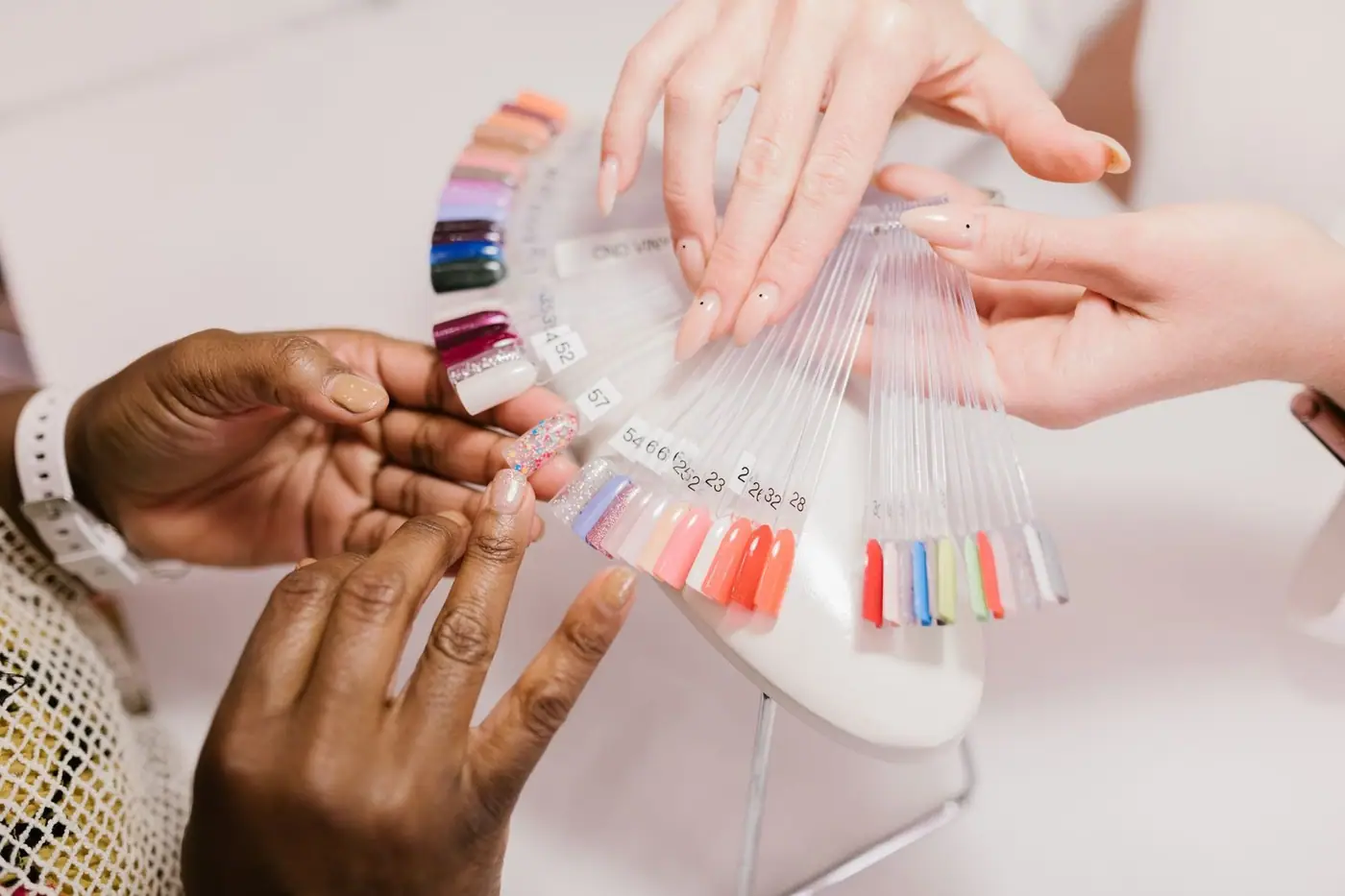 Close-up of hands choosing from a nail polish sample palette.