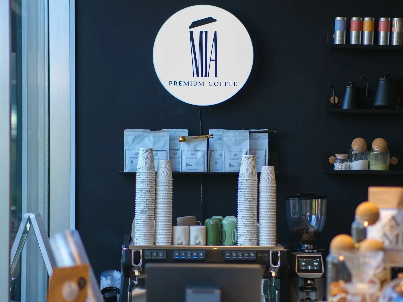 A stylish coffee shop interior with stacks of cups and coffee brewing equipment