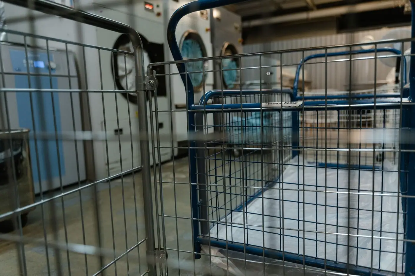 Empty metal baskets and commercial washing machines in a laundry facility