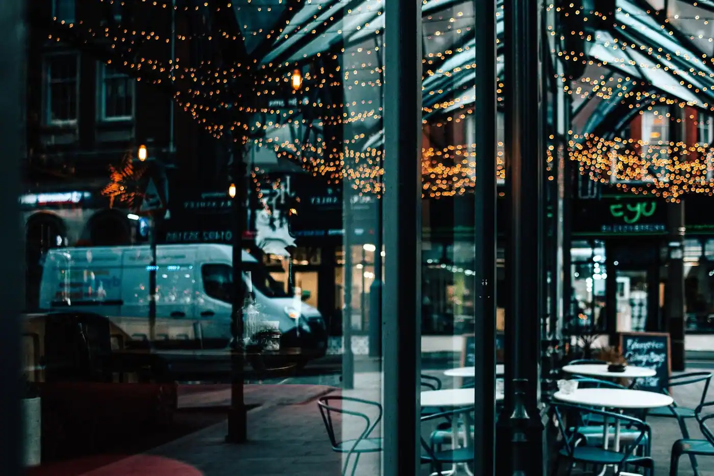 A bustling city scene reflected in a cafe window with warm bokeh lights