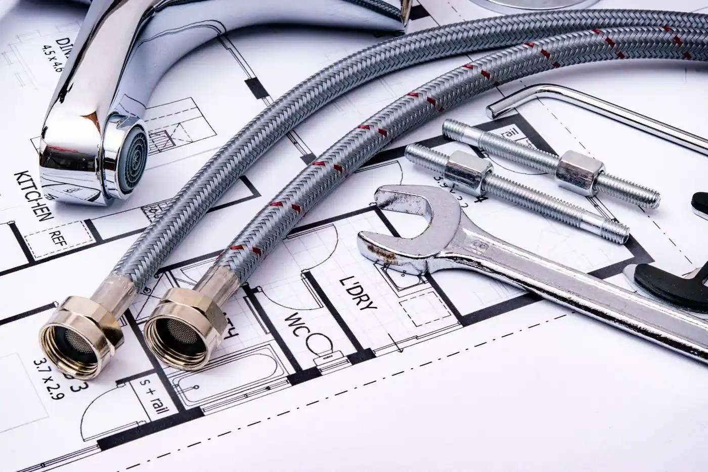 Close-up of plumbing tools and a tap laid on an architectural blueprint