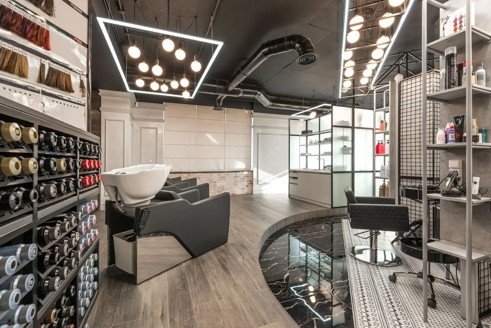 Black backwash chair with white sink placed in modern stylish beauty salon with various cosmetology products and bright 