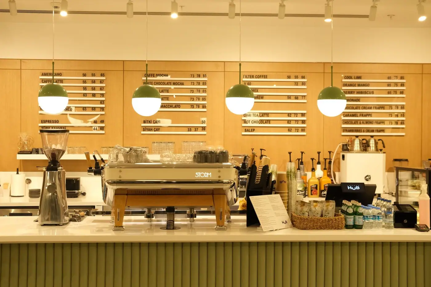 Café counter with an espresso machine and menu boards under warm lighting