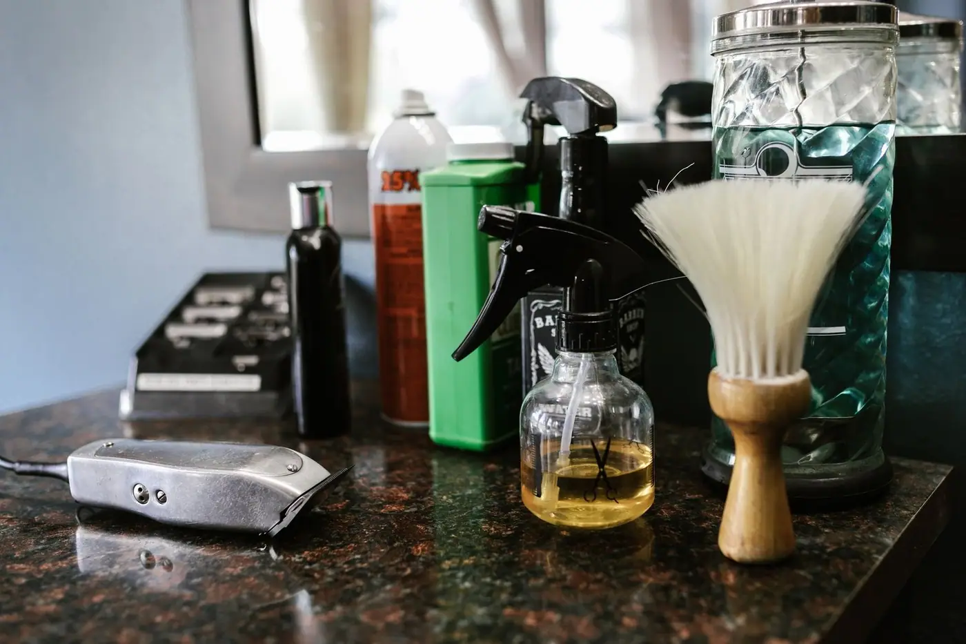 Close-up of barber tools on a counter, including clippers, a spray bottle and a brush