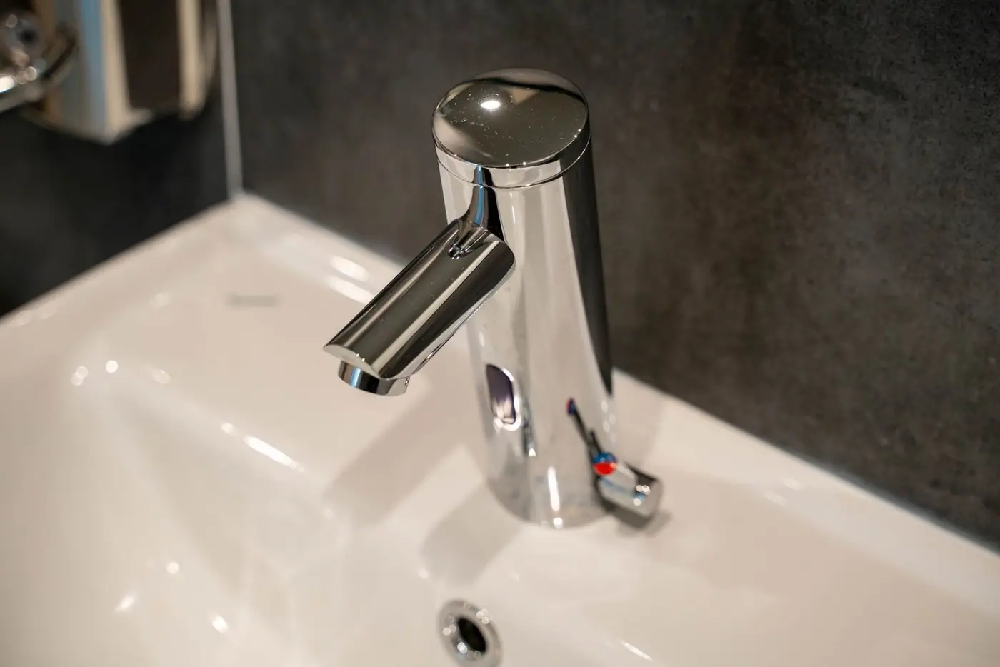 Close-up of a modern, shiny stainless steel tap on a ceramic sink