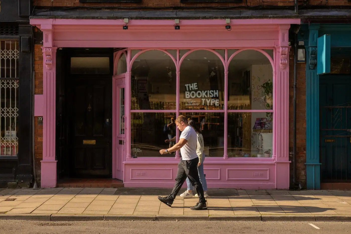 Pink shop facade on a sunny street with people walking by