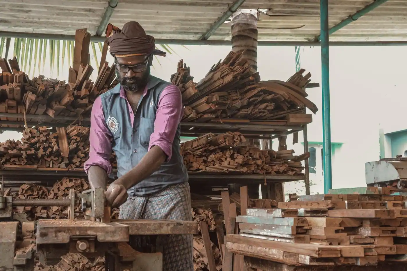 Carpenter demonstrating craftsmanship in a workshop filled with pieces of wood