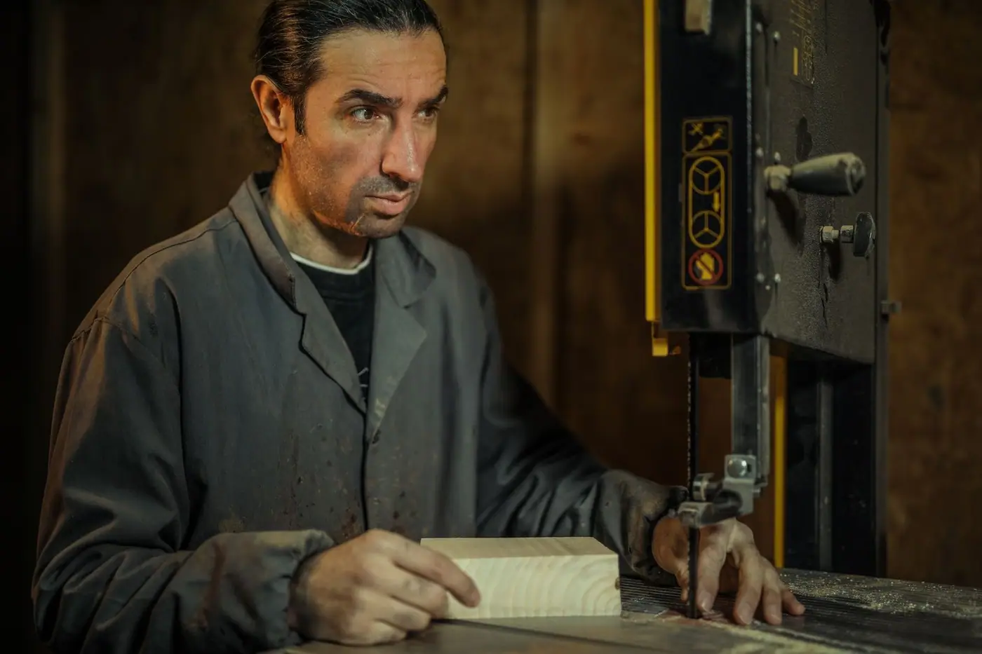 Carpenter operating a band saw while crafting wood in a workshop