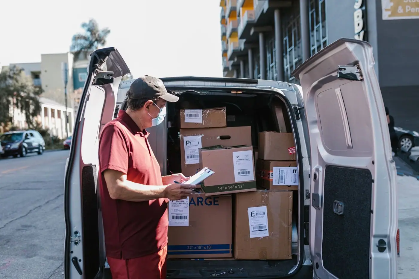 Delivery worker checks packages in a van on a city street.