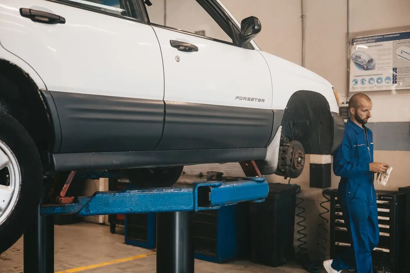 Mechanic evaluating a car on a lift for maintenance in an auto workshop