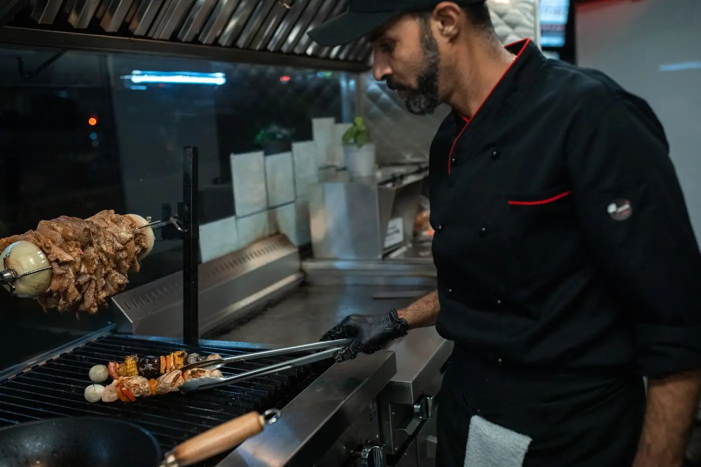 A chef grilling skewers in a professional kitchen