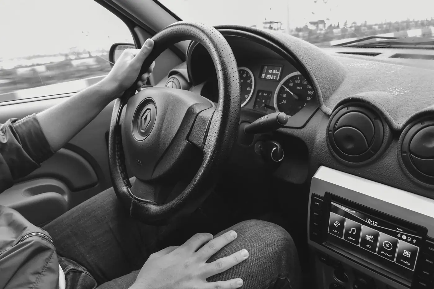 A driver's hands on the steering wheel inside a car cabin.