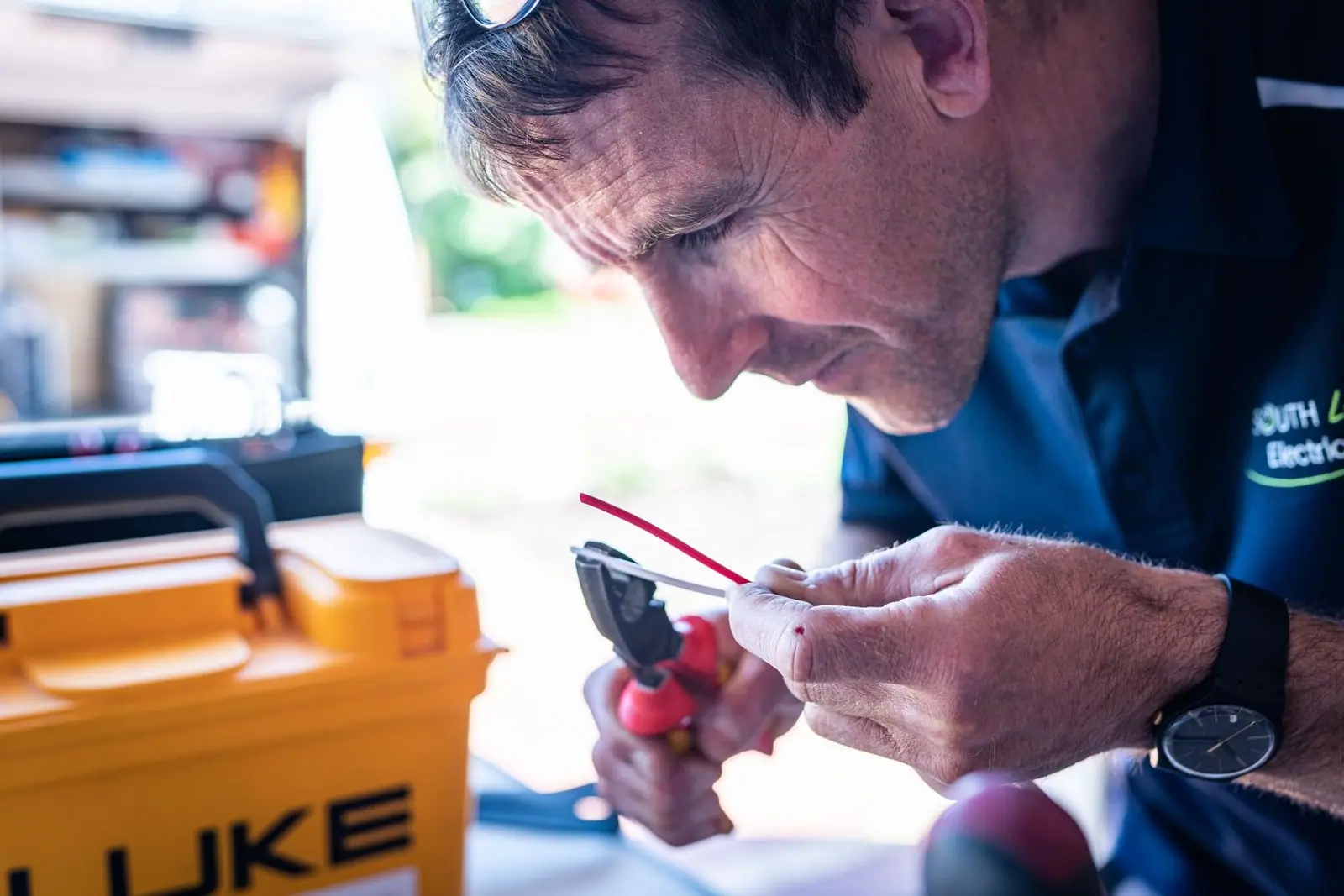 Focused technician working on wiring with tools in a workshop setting