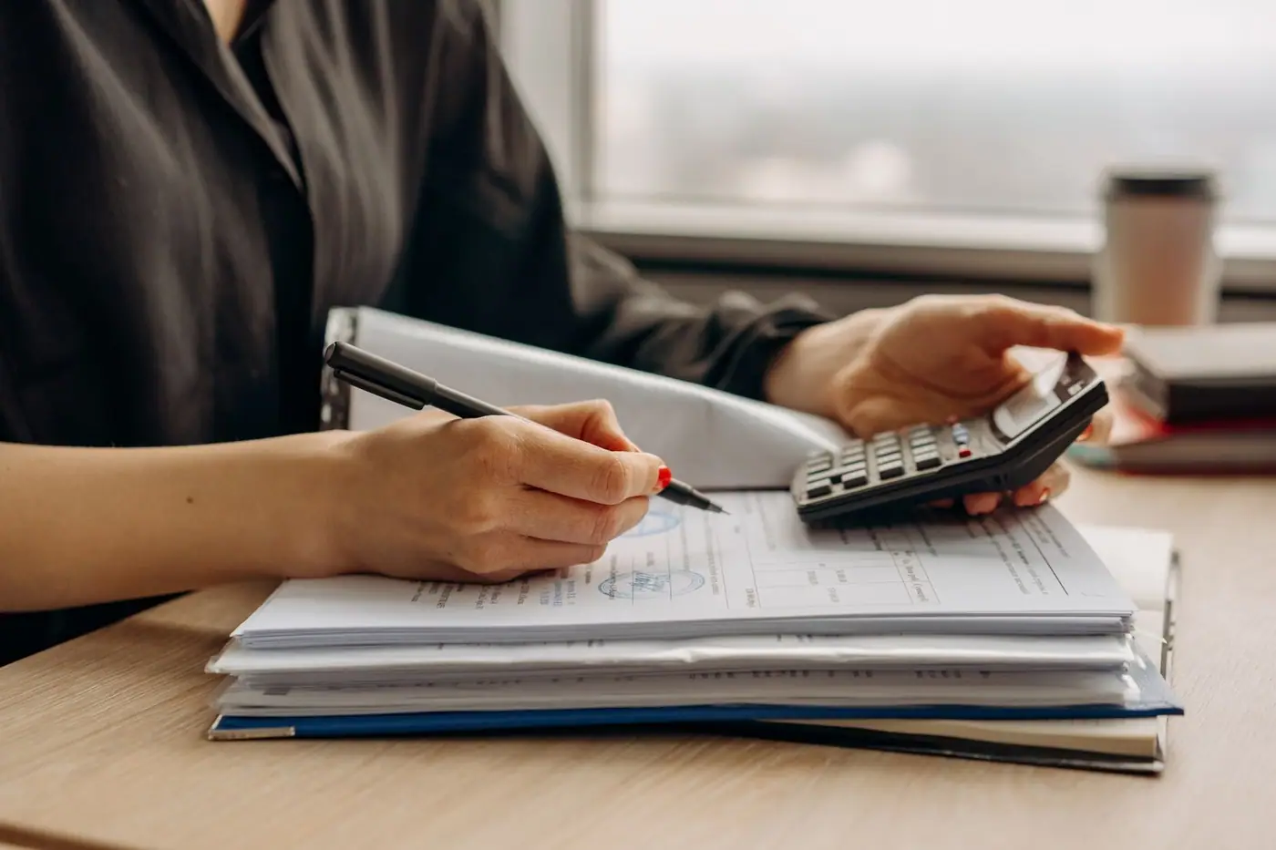 Close-up of a person using a calculator with financial documents in an office