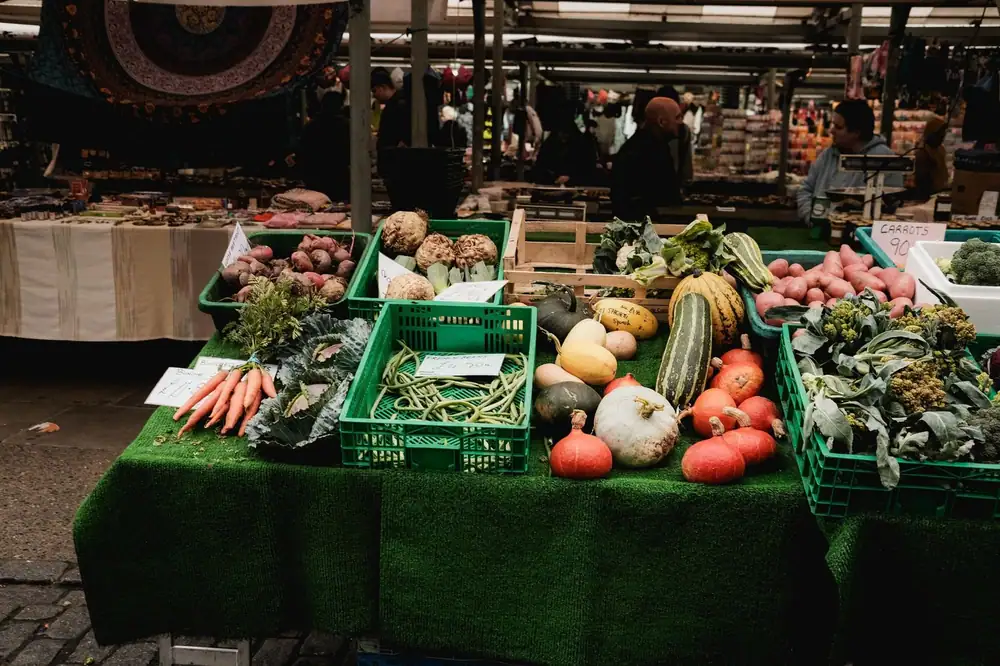 Colorful display of fresh vegetables at an outdoor farmers market stall.