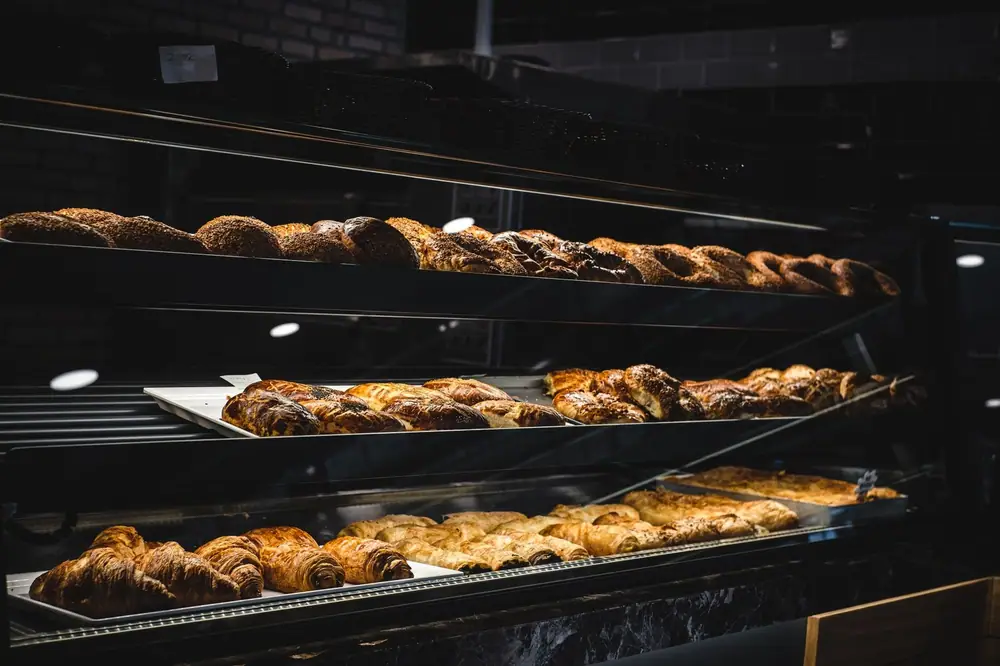 A variety of freshly baked pastries and breads in a glass display case at a bakery.