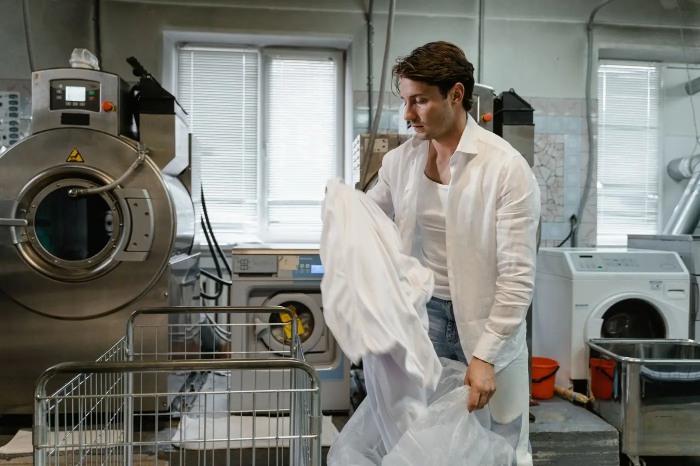 A man organising laundry beside large washing machines