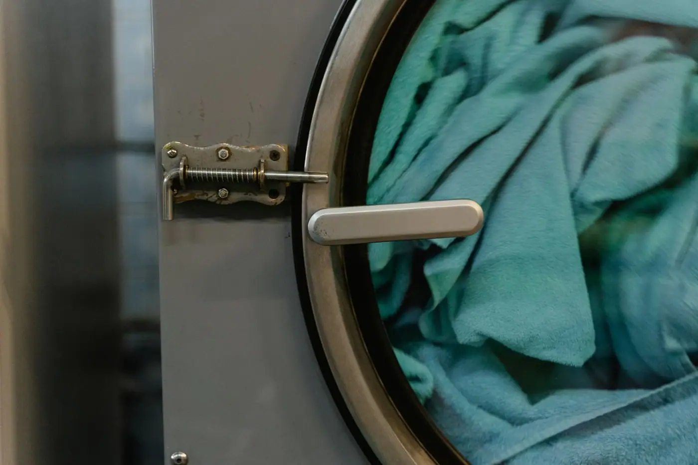 A commercial washing machine with blue fabric inside during a wash cycle