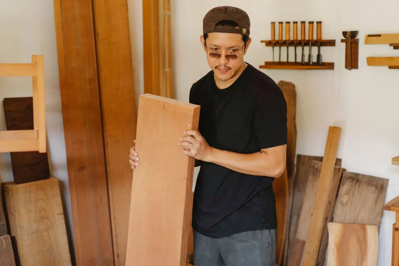 A man in casual clothes pondering, holding a timber plank in his arms