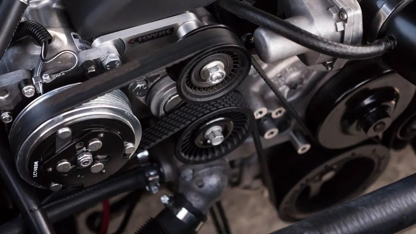 Close-up of a car engine bay showing serpentine belts, pulleys and polished aluminium components