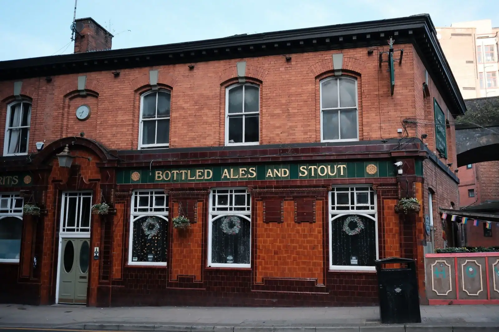 A classic red brick pub featuring signage for bottled ales and stout on a city street