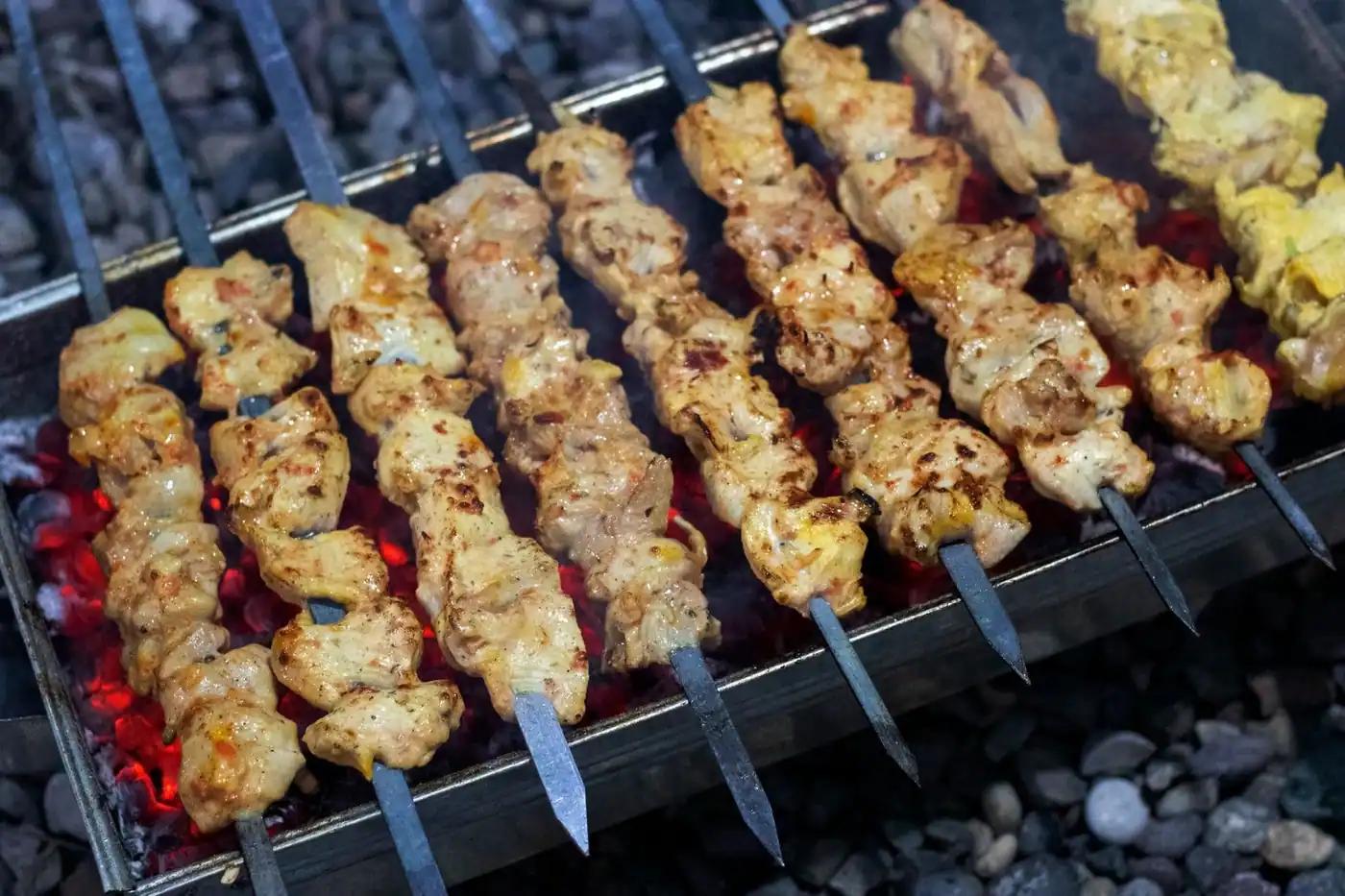 Chicken kebabs grilling over hot coals