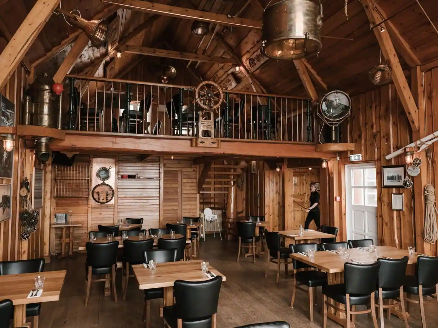 Restaurant interior with wooden walls, wooden tables, leather chairs and metal lamps
