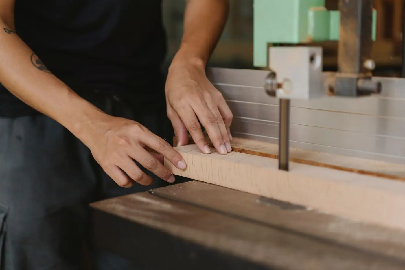 Joiner sawing a wooden block with an electric saw on a workroom table