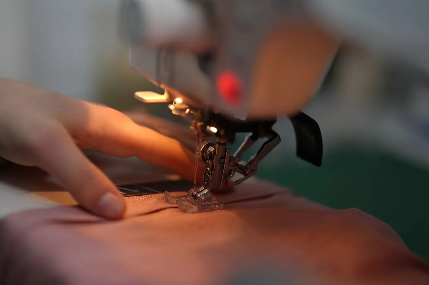 A hand guiding fabric through a sewing machine