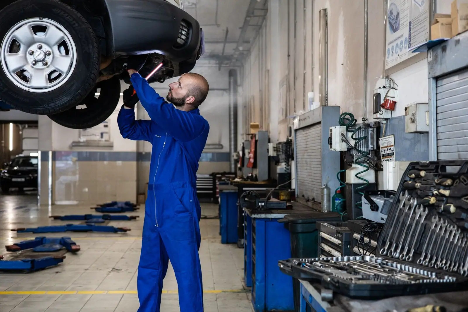 Mechanic inspecting a raised car in an auto workshop for maintenance and repair services