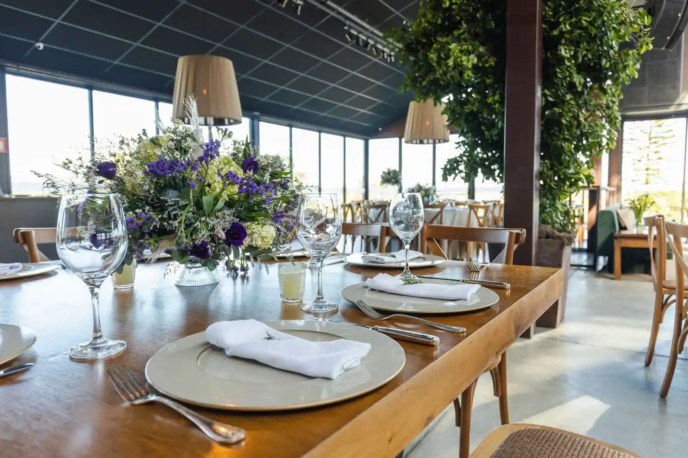 A beautifully arranged table setting in a well-lit hall with floral centrepieces