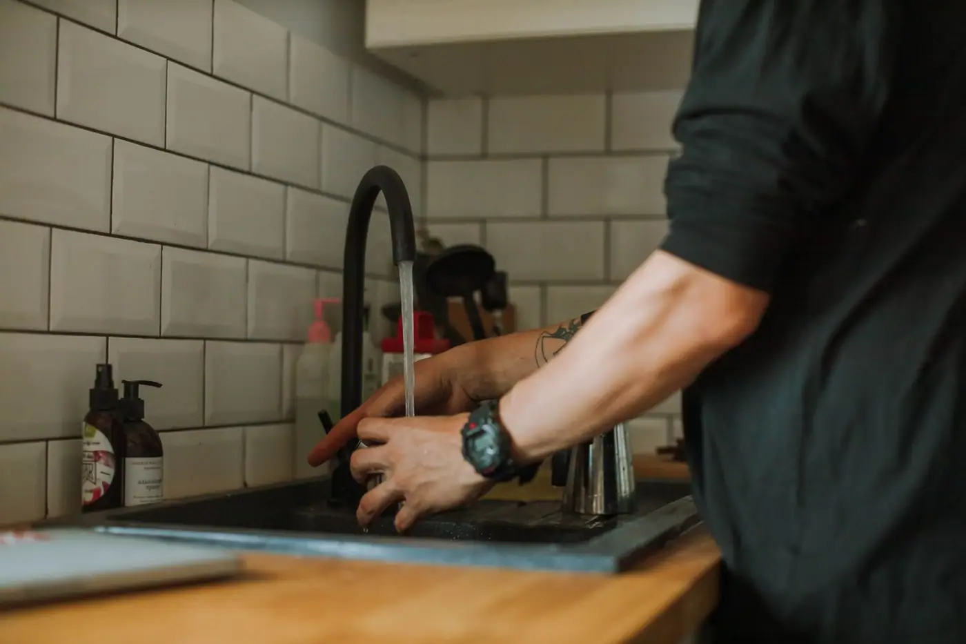Close-up of hands being washed at a sink under running water
