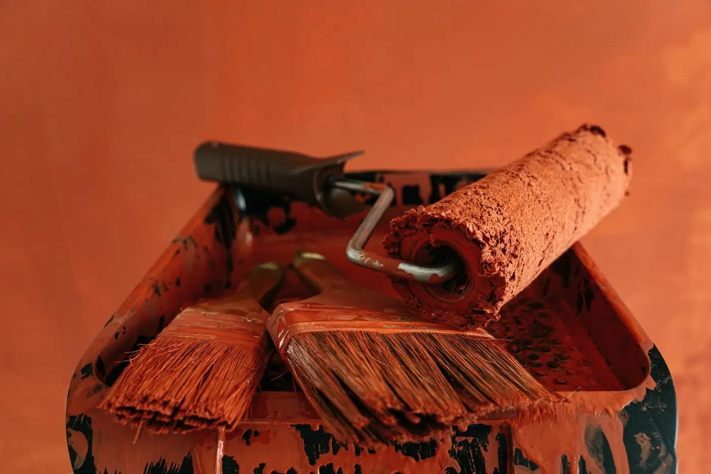 Orange paint tools in a messy paint tray.