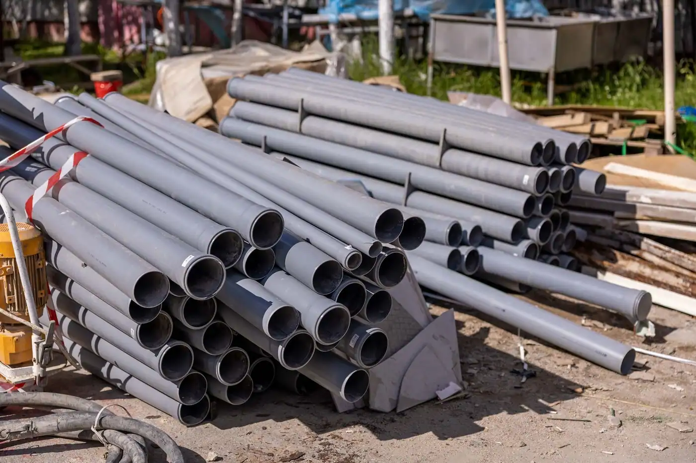 A collection of grey PVC pipes neatly stacked at an outdoor construction site