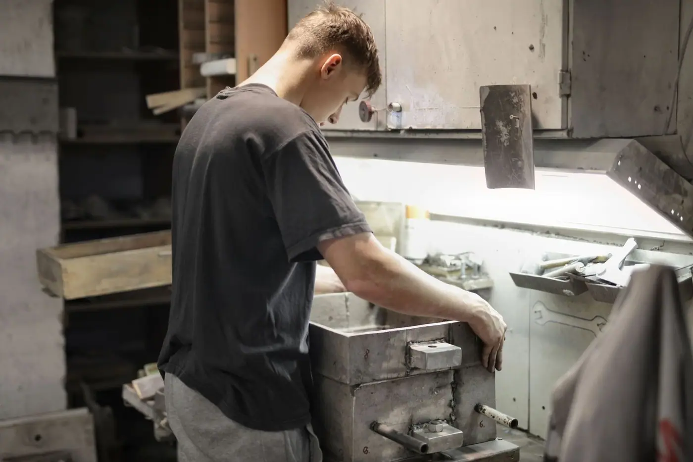 A young fitter examining a metal part on a workbench in a workshop
