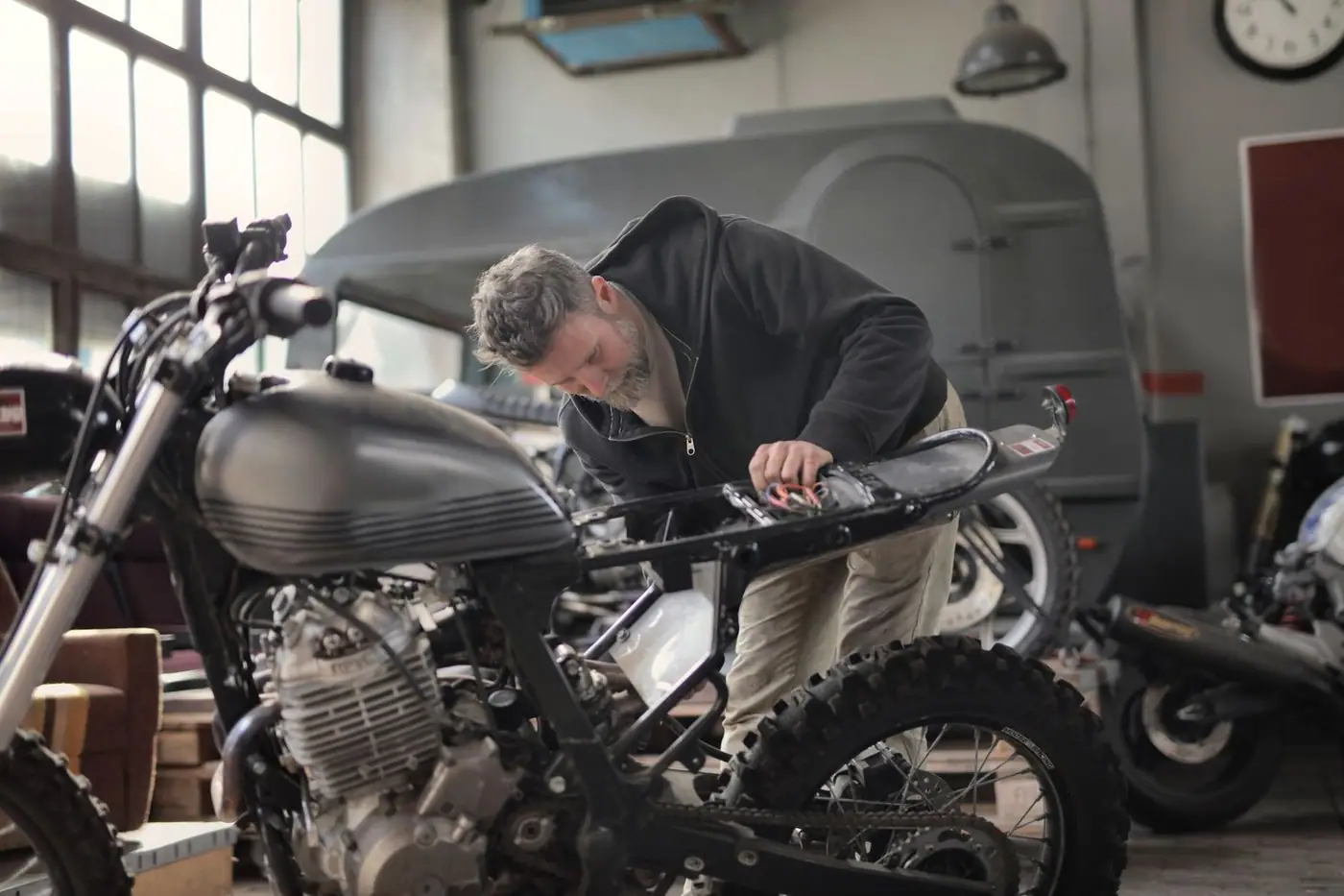 A mechanic working on a motorcycle inside an industrial style workshop