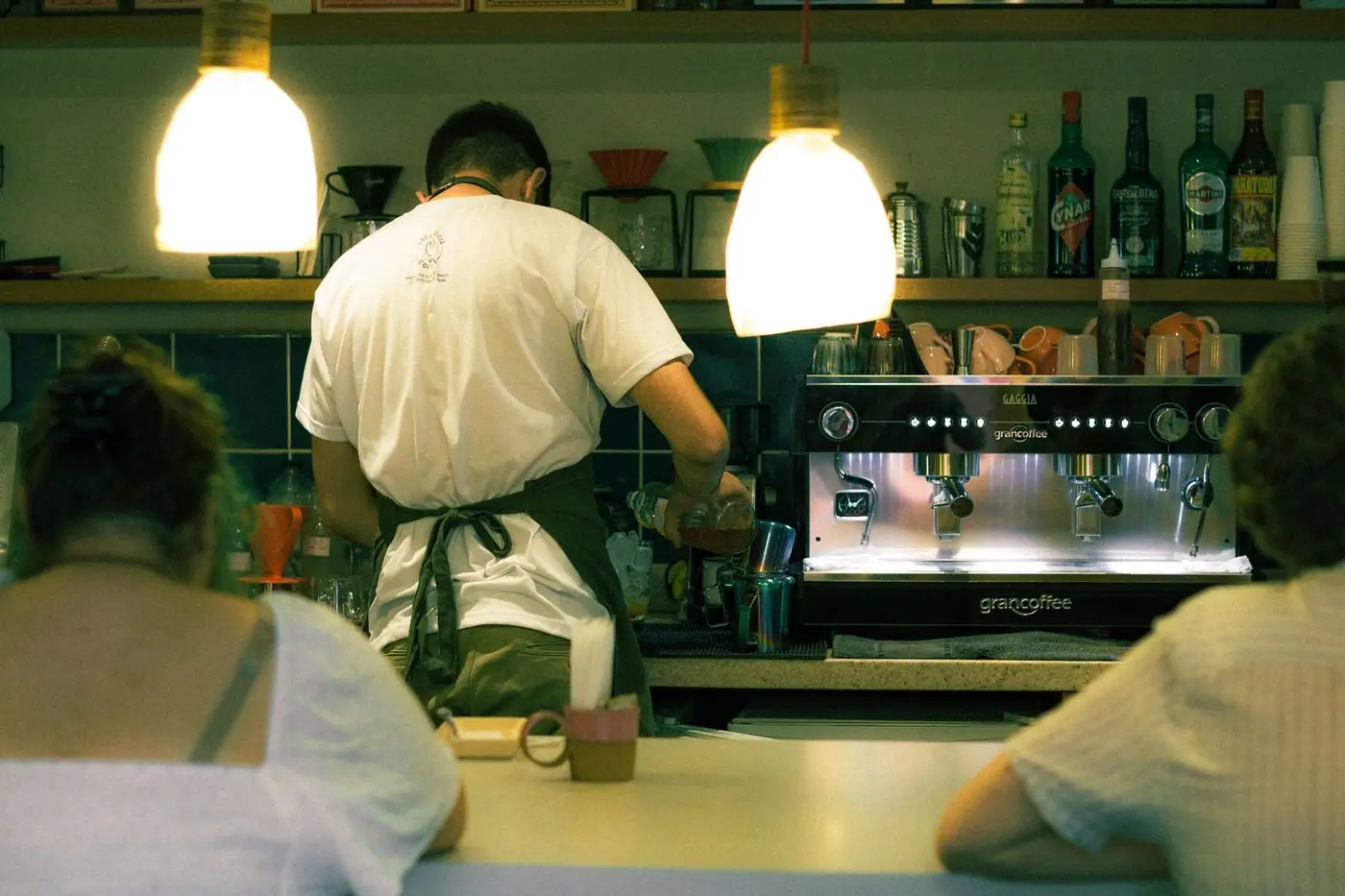 A barista preparing coffee at an espresso machine in a warmly lit café